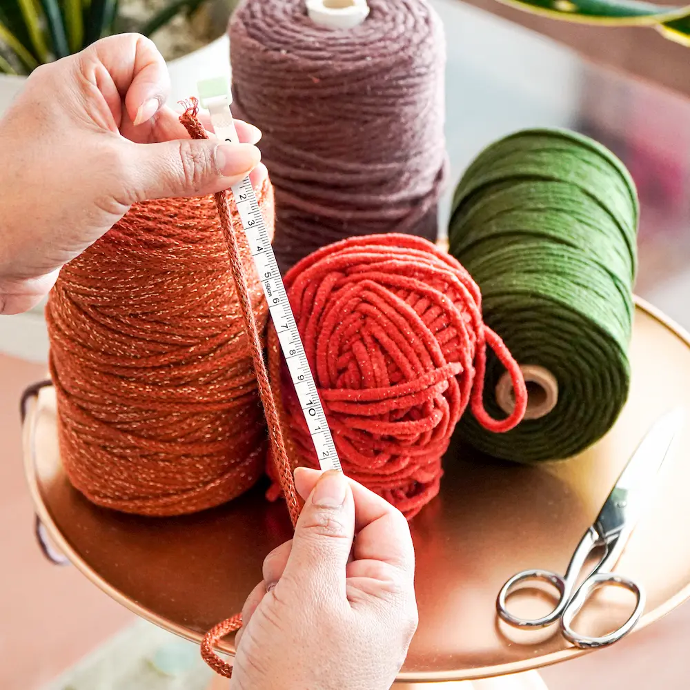 manos de mujer midiendo hilo de macrame con cinta metrica